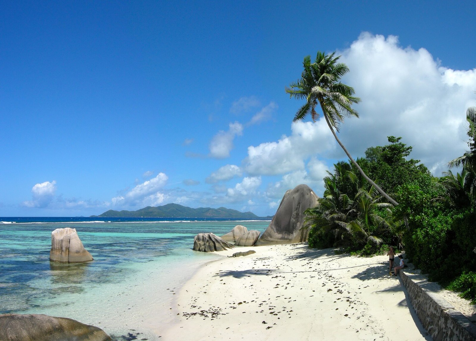 Graniittilohkareita ja kallistunut palmu Anse Source d'Argentilla La Diguella, Praslin horisontissa