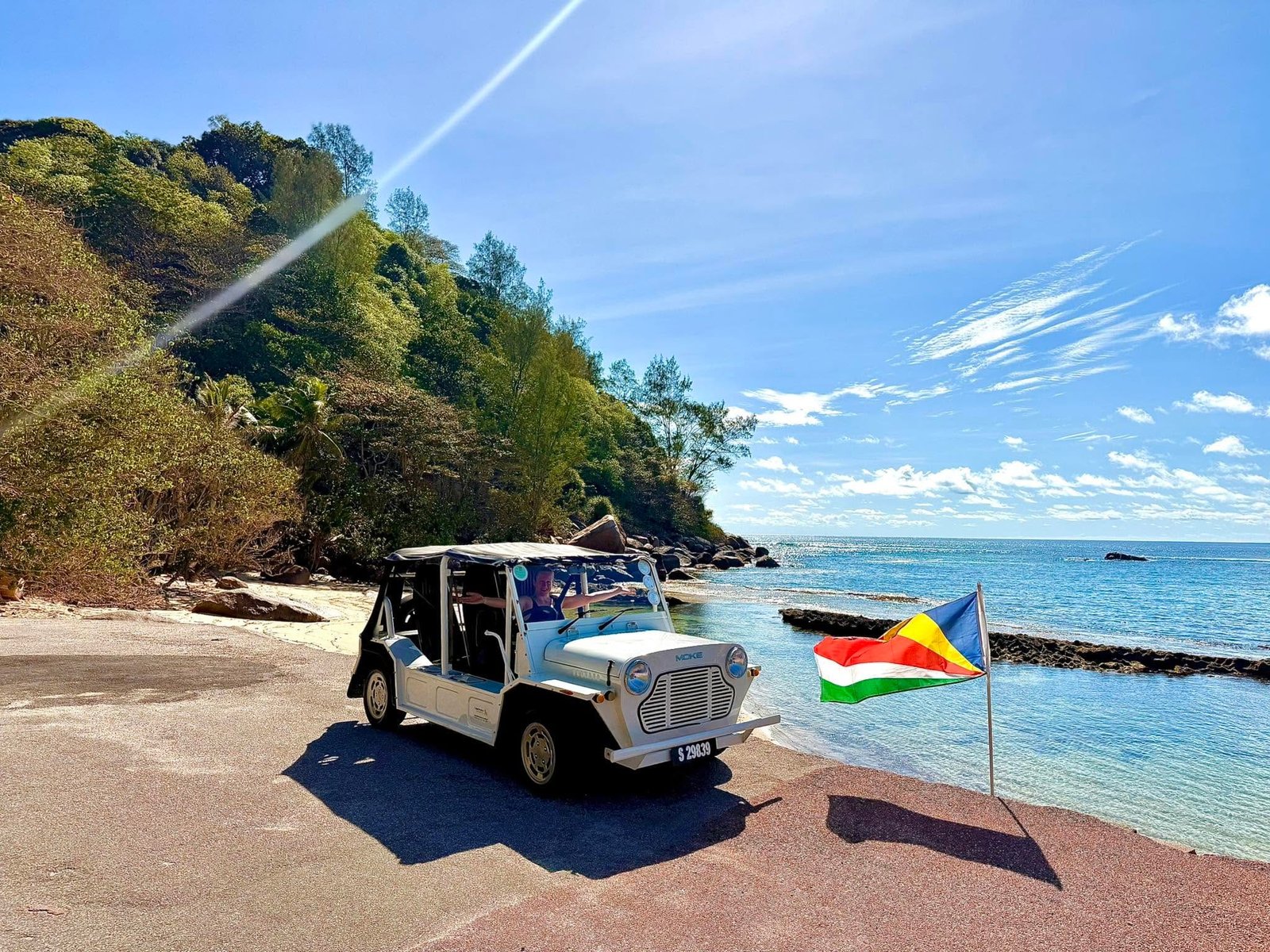 Valkoinen Mini Moke pysäköitynä laskuluiskalle Seychellien lipun viereen