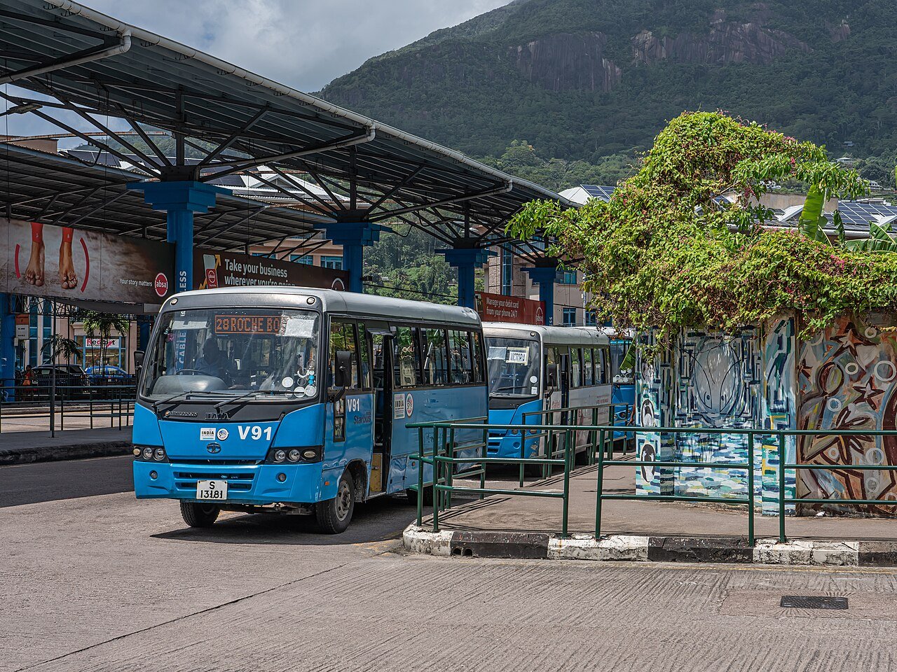Linja-autoasema sinisine busseineen katoksen alla, vuoret taustalla